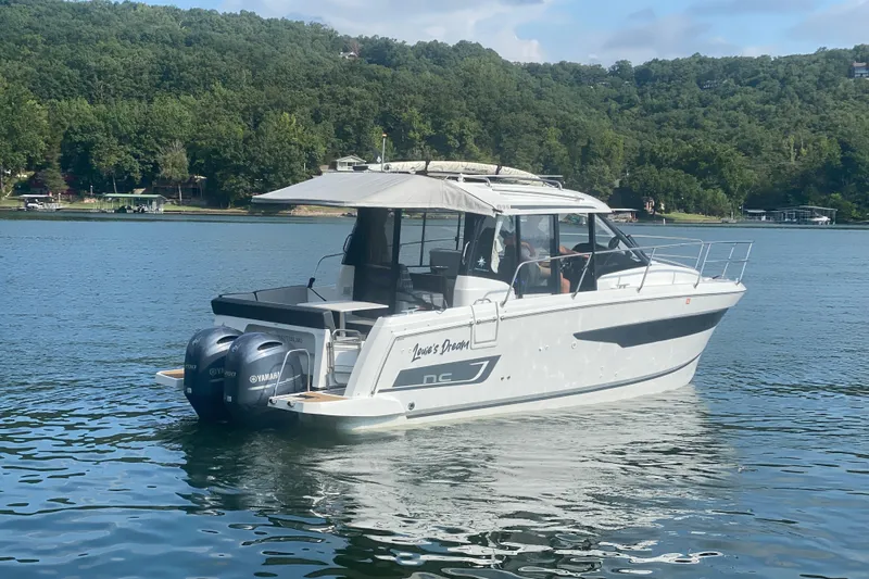  Yacht Photos Pics 2024 Jeanneau NC 895 boat on a serene lake with lush green shoreline.