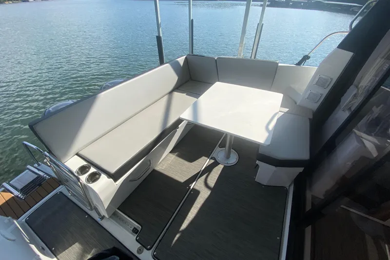  Yacht Photos Pics 2024 Jeanneau NC 895 boat interior with seating and table on calm water.
