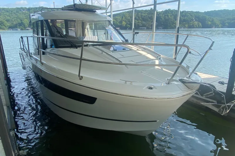  Yacht Photos Pics 2024 Jeanneau NC 895 boat docked on a serene lake with lush green hills.