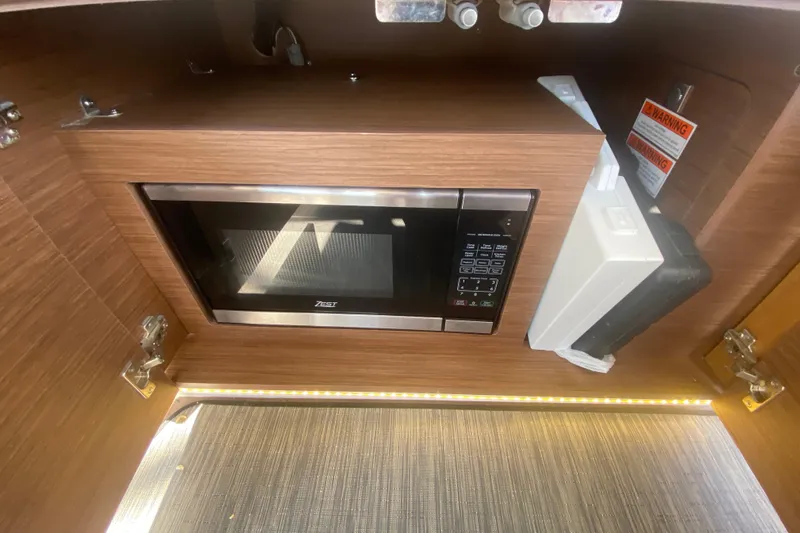  Yacht Photos Pics 2024 Jeanneau NC 895 interior with built-in microwave and wooden cabinetry.
