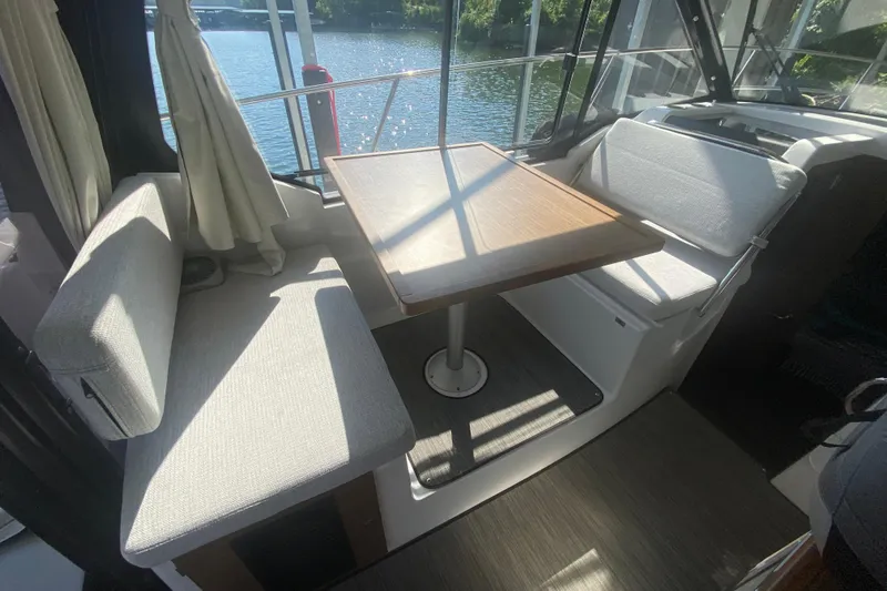  Yacht Photos Pics 2024 Jeanneau NC 895 interior dining area with table and cushioned seating.