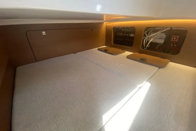  Yacht Photos Pics 2024 Jeanneau NC 895 cabin interior with control panel and cozy bedding.