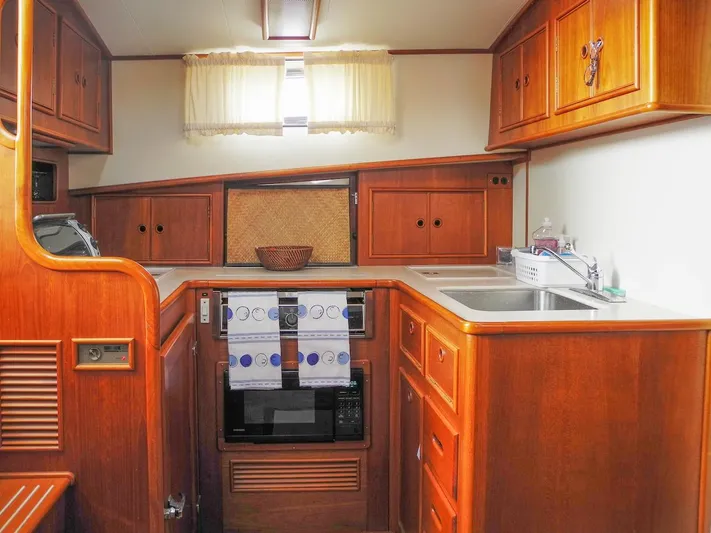 Salty Witch Yacht Photos Pics 1998 Grand Banks 38 Eastbay EX yacht kitchen with wooden cabinetry and modern appliances.