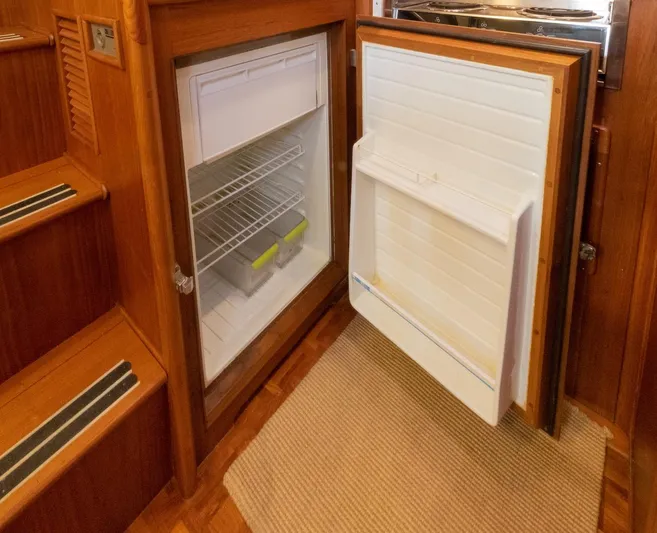 Salty Witch Yacht Photos Pics Open refrigerator inside 1998 Grand Banks 38 Eastbay EX yacht, showcasing wooden interior design.