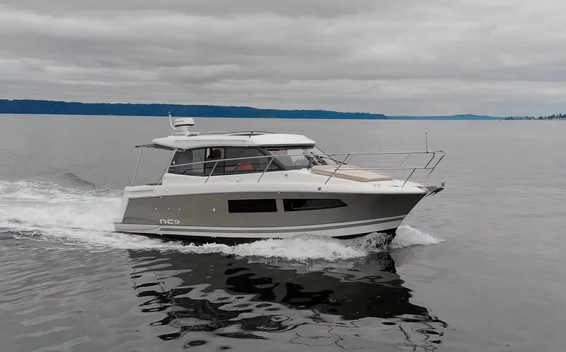 Myrt Yacht Photos Pics 2016 Jeanneau NC9 cruising on calm waters under cloudy skies.