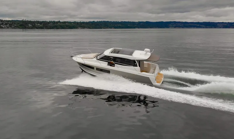 Myrt Yacht Photos Pics 2016 Jeanneau NC9 motor yacht cruising on calm waters under cloudy skies.