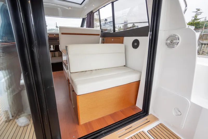 Myrt Yacht Photos Pics Interior view of 2016 Jeanneau NC9 boat with white seating and wooden flooring.