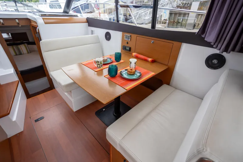 Myrt Yacht Photos Pics 2016 Jeanneau NC9 interior dining area with table, cushioned seating, and tableware.