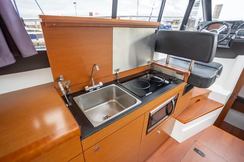 Myrt Yacht Photos Pics 2016 Jeanneau NC9 yacht kitchen with sink, stove, and seating.