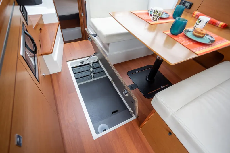 Myrt Yacht Photos Pics 2016 Jeanneau NC9 interior with open storage hatch, dining area, and modern decor.