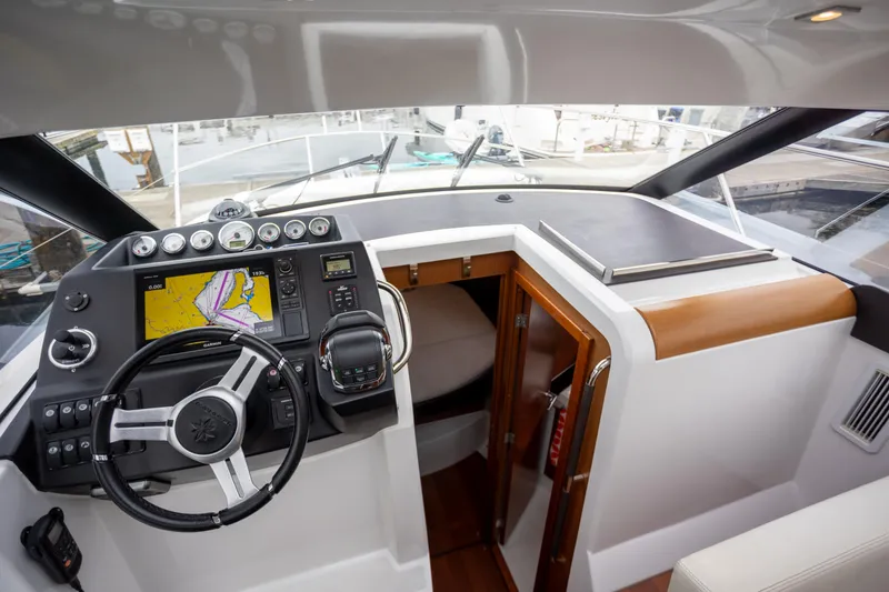 Myrt Yacht Photos Pics 2016 Jeanneau NC9 helm with navigation system and wooden cabin entrance.