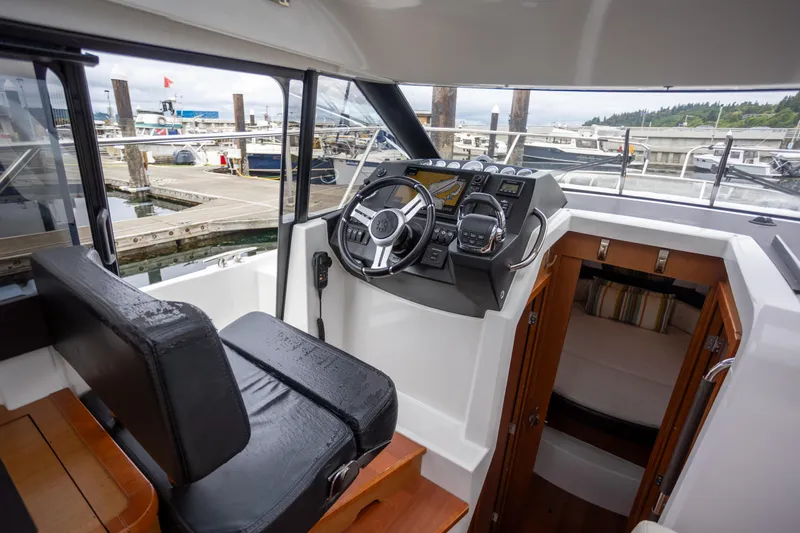 Myrt Yacht Photos Pics Interior view of 2016 Jeanneau NC9 boat cockpit with steering wheel and cabin entrance.
