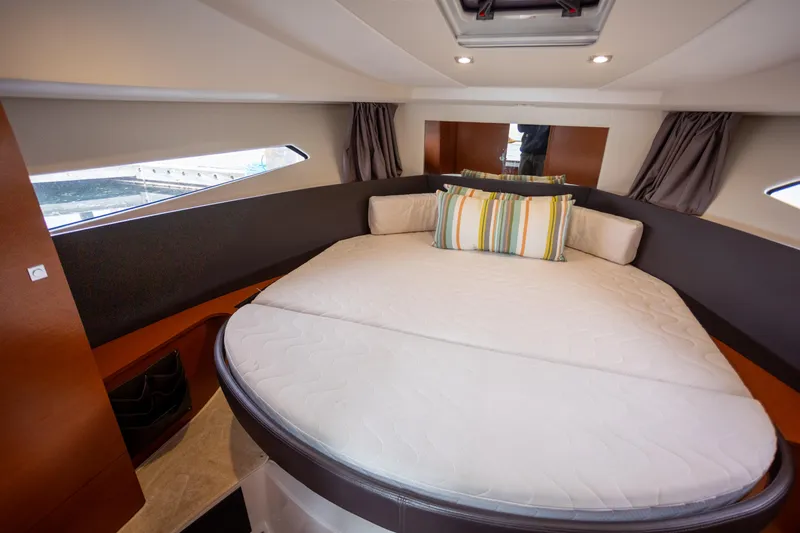 Myrt Yacht Photos Pics 2016 Jeanneau NC9 cabin with round bed, striped pillows, and modern design.