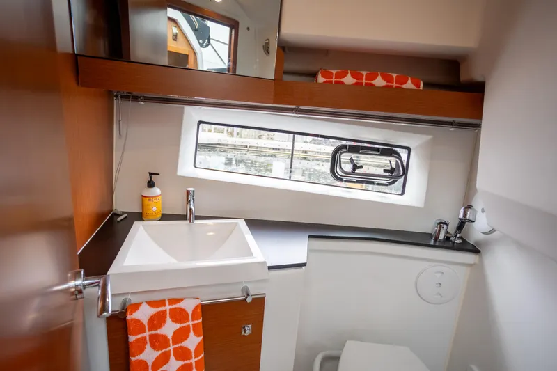 Myrt Yacht Photos Pics 2016 Jeanneau NC9 bathroom with modern sink, window, and orange accents.