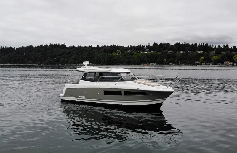 Myrt Yacht Photos Pics 2016 Jeanneau NC9 boat cruising on a calm lake with forested shoreline.