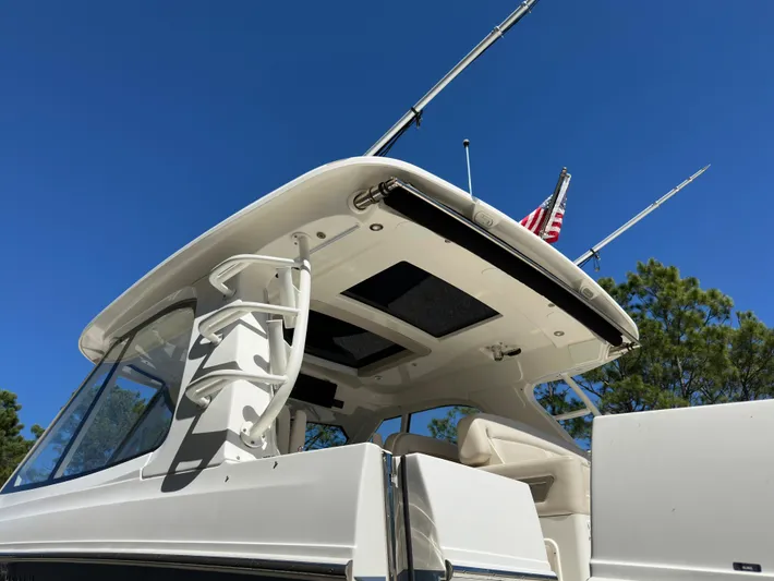 Dream Chaser Yacht Photos Pics 2021 Boston Whaler Realm 380 boat with fishing rods and American flag against blue sky.