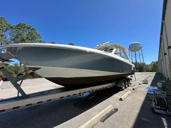 Dream Chaser Yacht Photos Pics 2021 Boston Whaler Realm 380 boat on trailer, parked outdoors under clear blue sky.