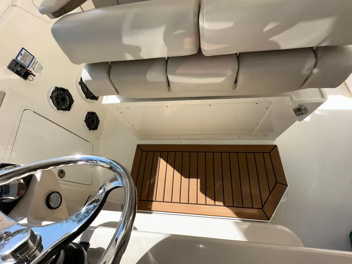 Dream Chaser Yacht Photos Pics 2021 Boston Whaler Realm 380 helm area with cushioned seating and wooden flooring.