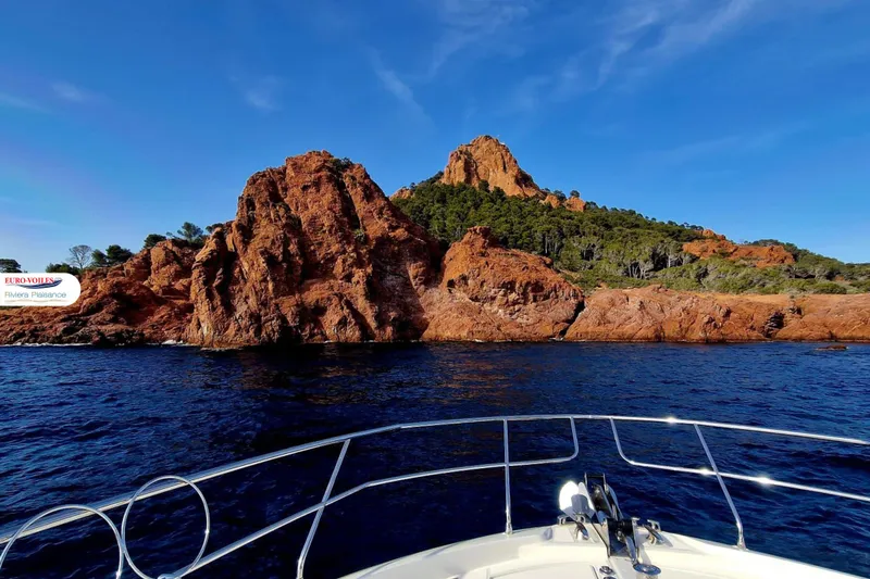 Sea Change Yacht Photos Pics Prestige 590 Fly yacht cruising near rocky coastline under clear blue sky, 2021 model.