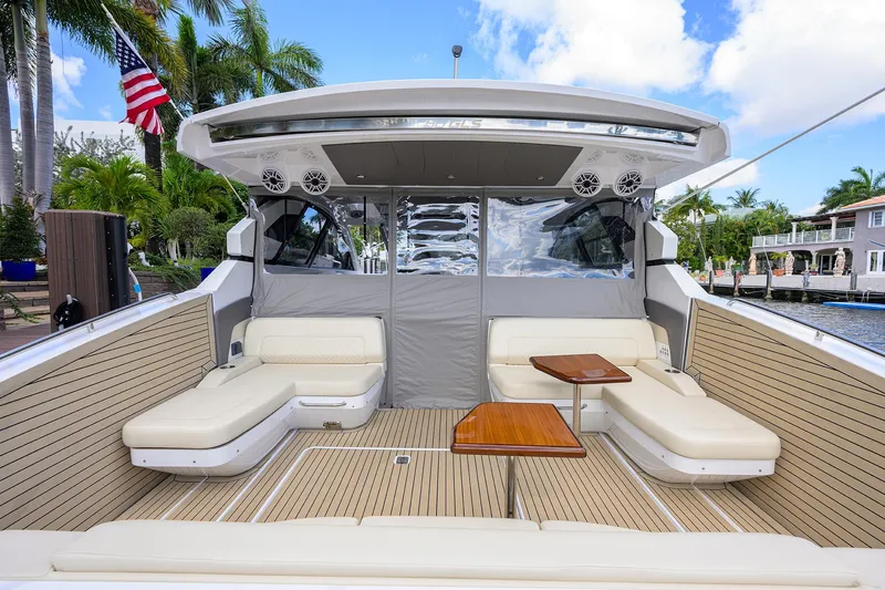 2024 Cruisers Yachts 50 Gls Outboard Yacht Photos Pics 2024 Cruisers Yachts GLS-OB luxury boat interior with seating and tables, docked near palm trees.