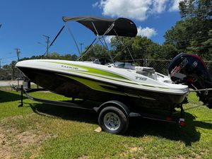 2024 Tahoe T18 boat on trailer, green and white design, parked on grass under blue sky.