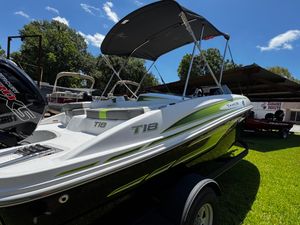 2024 Tahoe T18 boat with canopy, parked on grass under a clear blue sky.