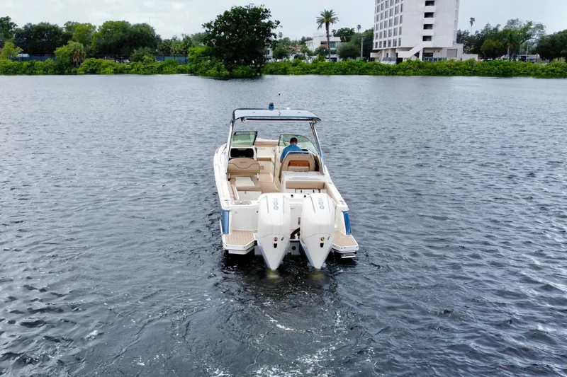  Yacht Photos Pics 2023 Chris-Craft Calypso 28 boat cruising on a calm lake near a cityscape.