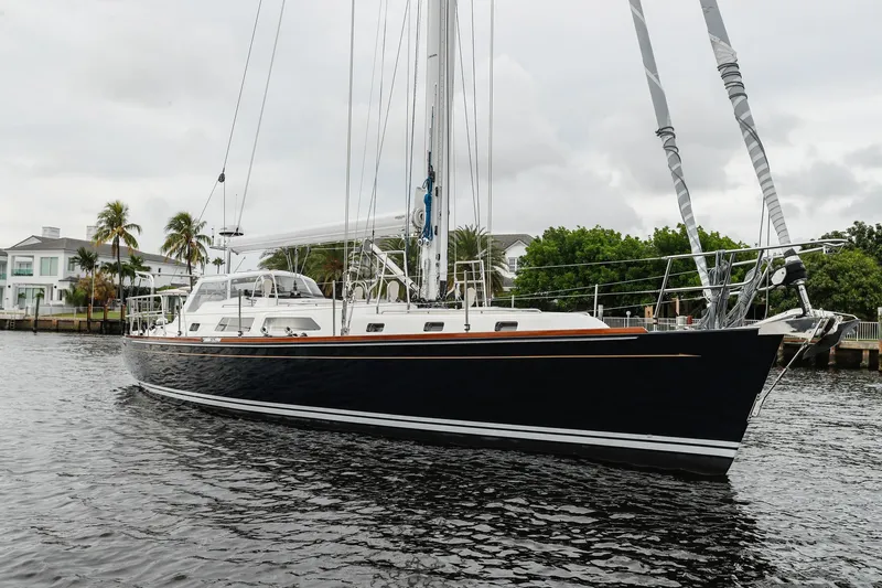 Outbound 46 Yacht Photos Pics Outbound 46 sailboat, 2025 model, docked on a calm waterway with lush greenery.