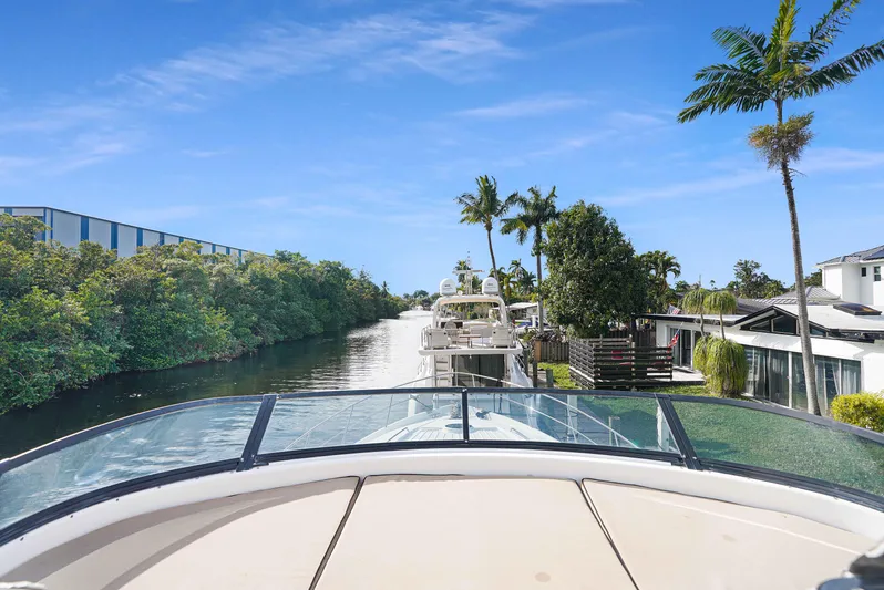 Carrie Ann Yacht Photos Pics 2006 Neptunus 62 Flybridge yacht cruising along a scenic canal with palm trees.