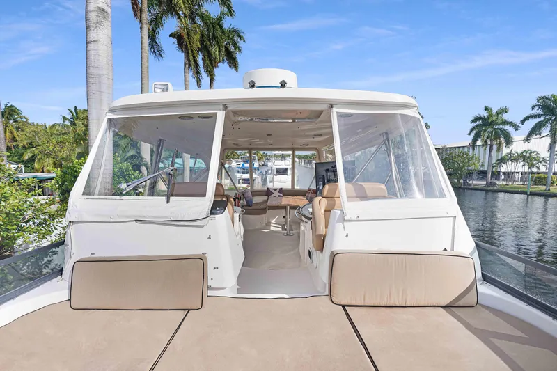 Carrie Ann Yacht Photos Pics 2006 Neptunus 62 Flybridge yacht with spacious deck and clear canopy, docked by palm trees.