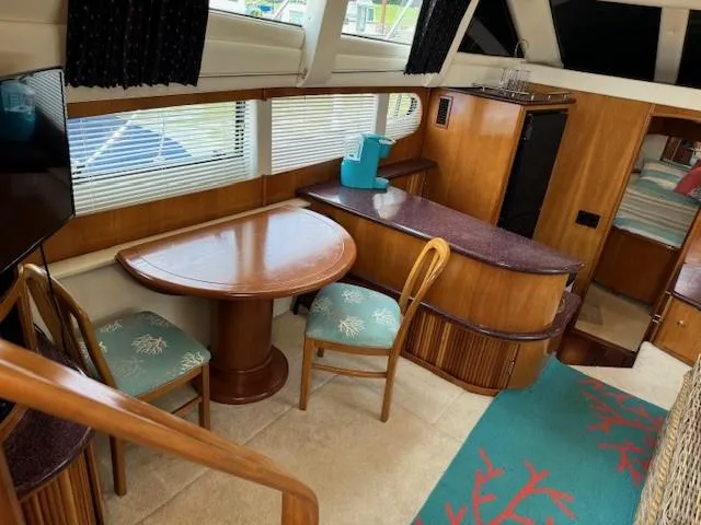 Wahooy Yacht Photos Pics Interior of 2001 Carver 396 Motoryacht with dining area, wooden furnishings, and teal accents.