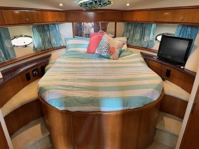 Wahooy Yacht Photos Pics 2001 Carver 396 Motoryacht bedroom with striped bedding, pillows, and a small TV.