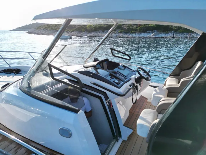  Yacht Photos Pics 2022 Sessa Marine Key Largo 40 yacht cockpit with modern controls and seating, near scenic coastline.