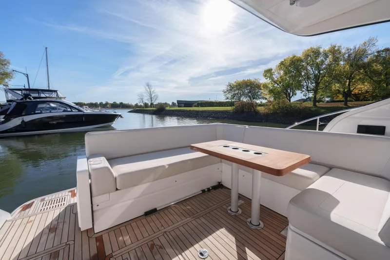  Yacht Photos Pics 2023 Fairline Targa 50 yacht deck with seating and table, docked near trees.