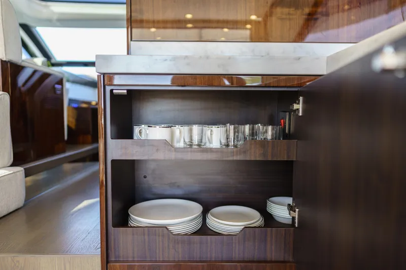  Yacht Photos Pics Luxury yacht interior with open cabinet displaying dishes and glassware, Fairline Targa 50, 2023 model.