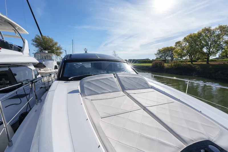  Yacht Photos Pics 2023 Fairline Targa 50 yacht with sunbed, docked near lush greenery.