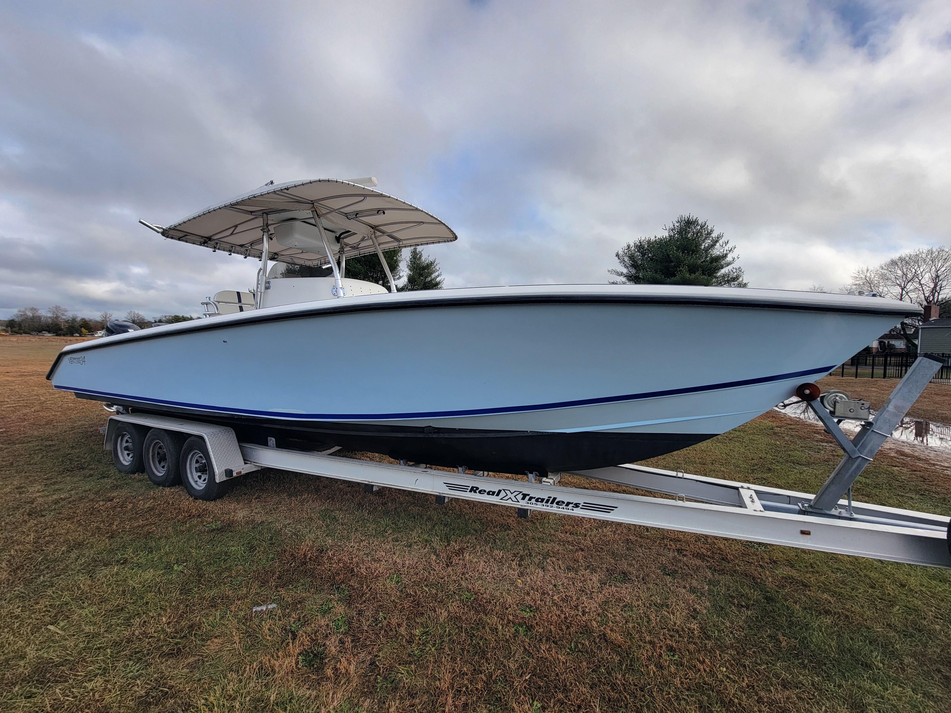 1996 Venture 34 Center Console boat on trailer, parked on grass under cloudy sky.