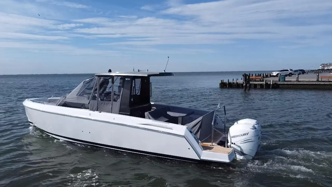 2023 Schaefer V33 boat cruising on open water near a dock.