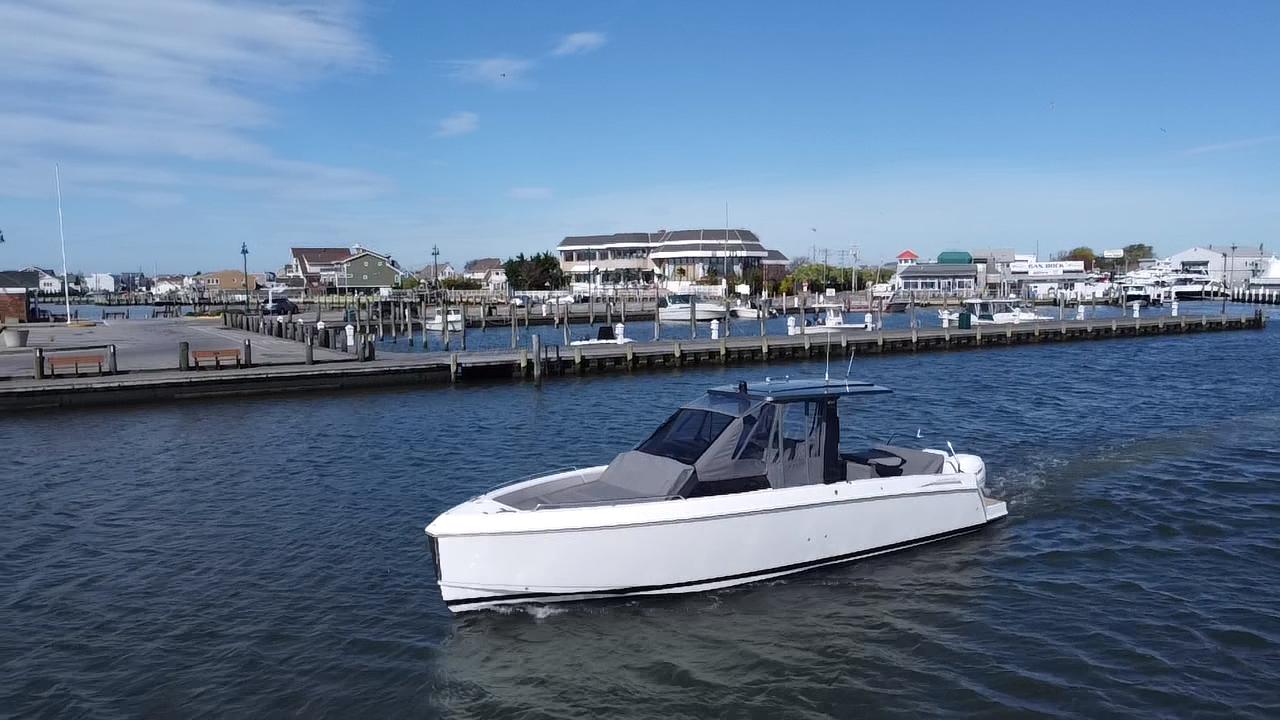 2023 Schaefer V33 boat cruising in a marina under a clear blue sky.