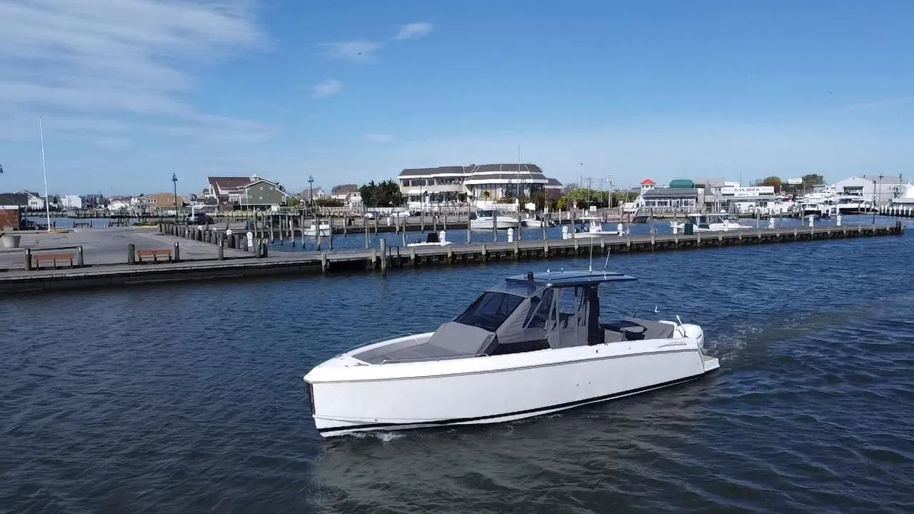 2023 Schaefer V33 boat cruising in a marina under a clear blue sky.