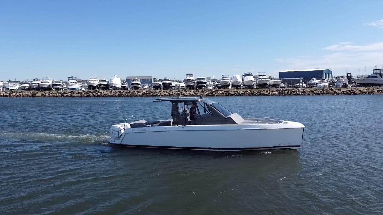 2023 Schaefer V33 boat cruising on a calm waterway with marina in background.