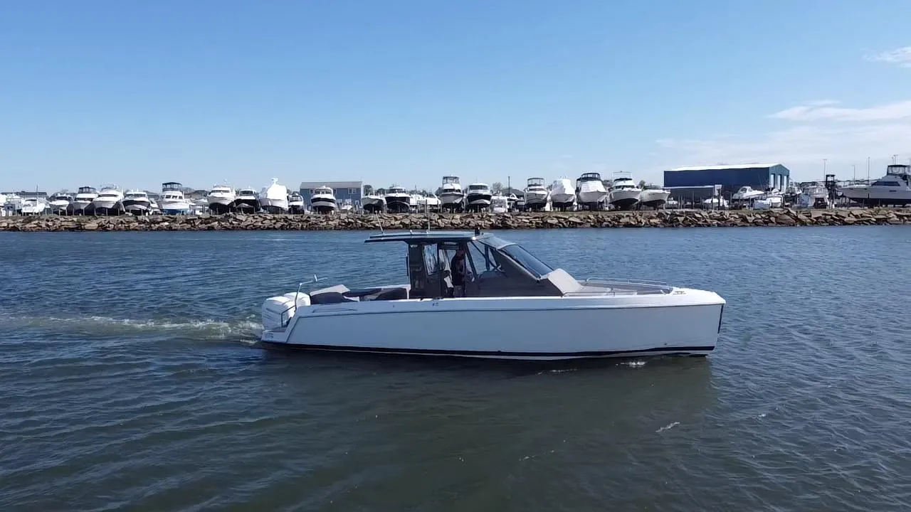 2023 Schaefer V33 boat cruising on a calm waterway with marina in background.