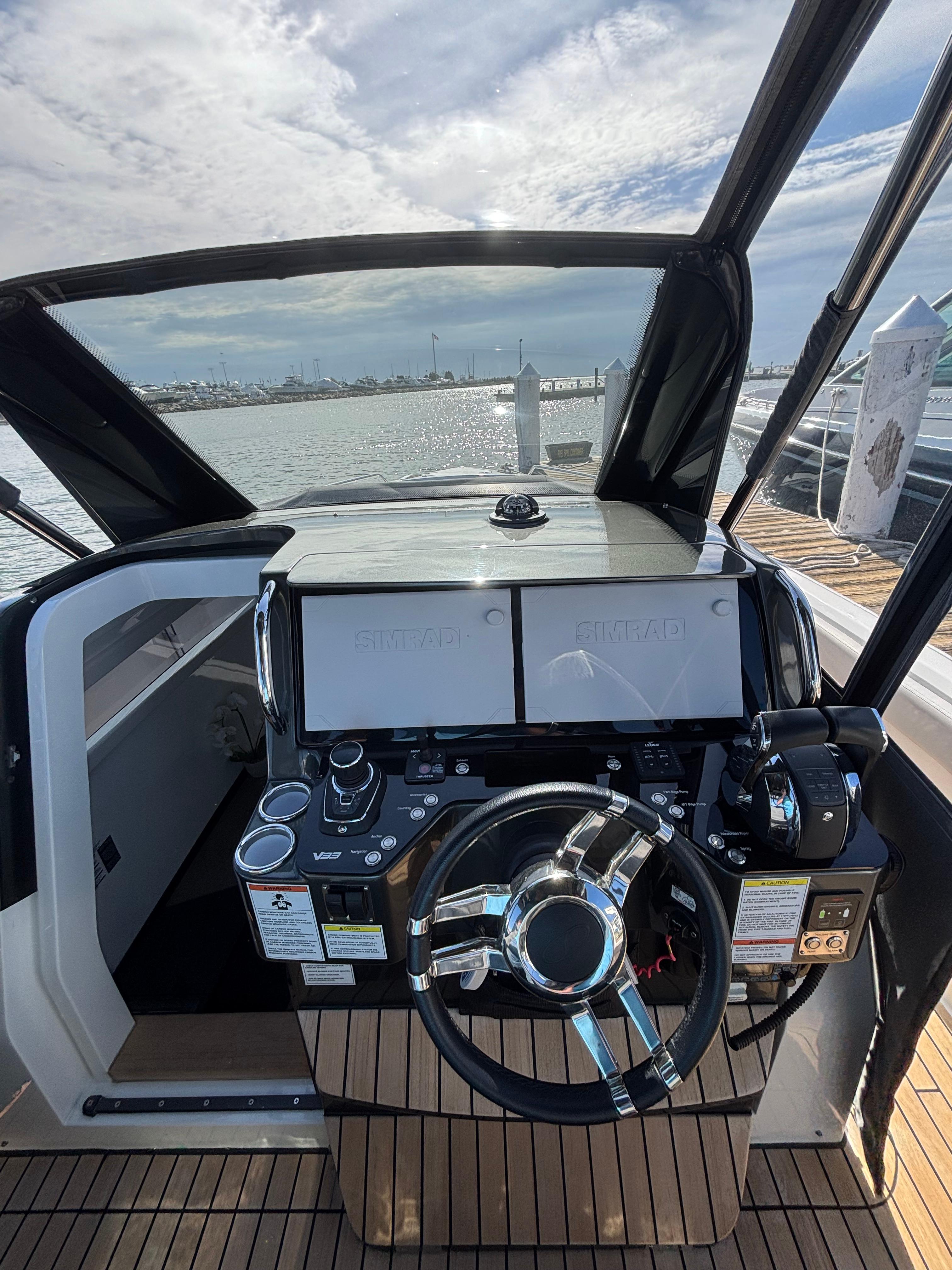2023 Schaefer V33 yacht helm with modern controls and dual screens, overlooking a scenic water view.