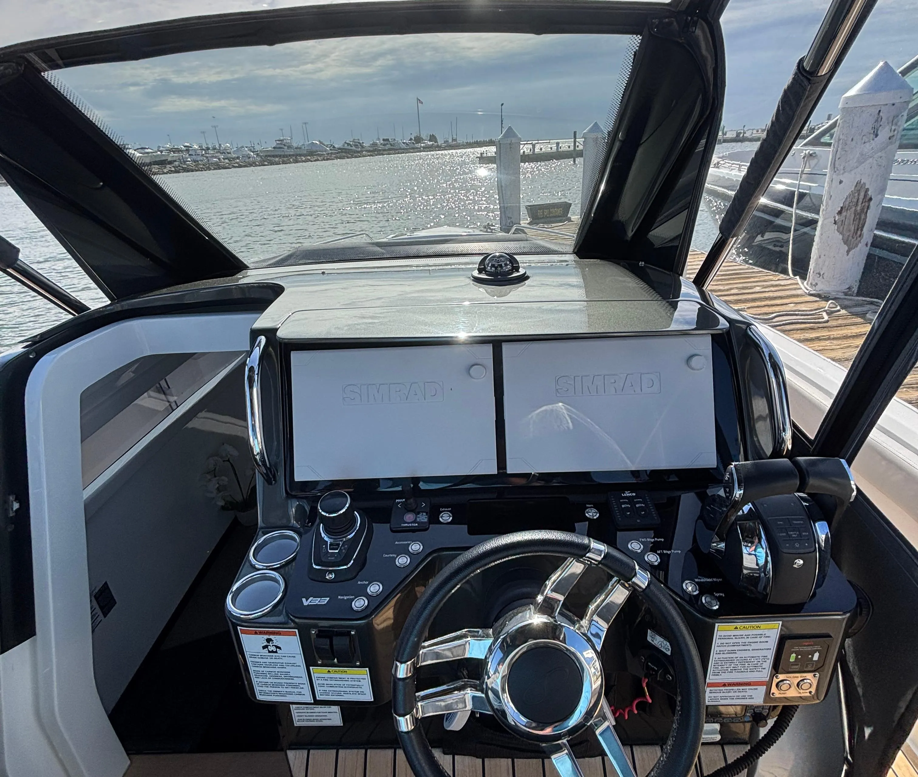2023 Schaefer V33 yacht helm with modern controls and dual screens, overlooking a scenic water view.
