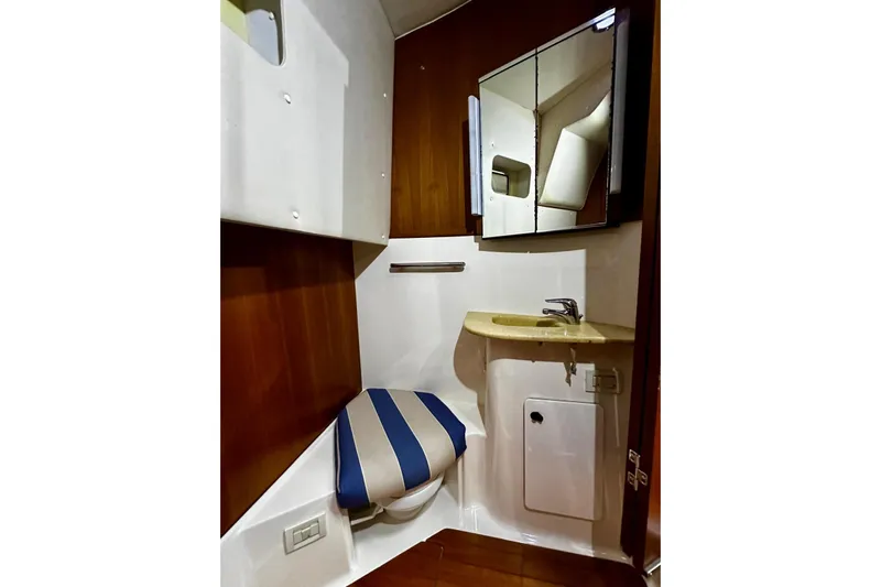  Yacht Photos Pics 2003 Tiara Yachts 4000 Express bathroom with striped seat, sink, and mirrored cabinet.