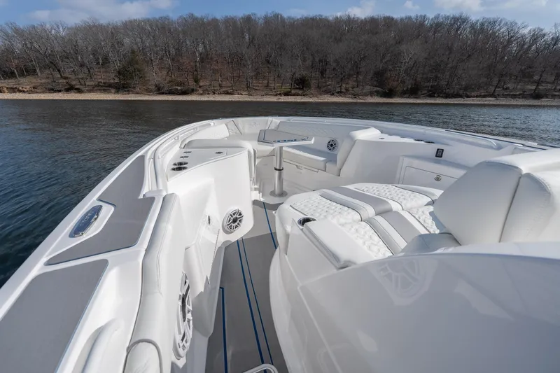  Yacht Photos Pics 2026 Fountain 43 SCX boat interior with luxurious seating, on a calm lake near a wooded shoreline.