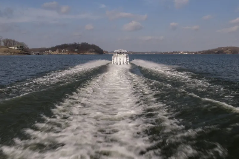  Yacht Photos Pics 2026 Fountain 43 SCX boat creating waves on a scenic lake.