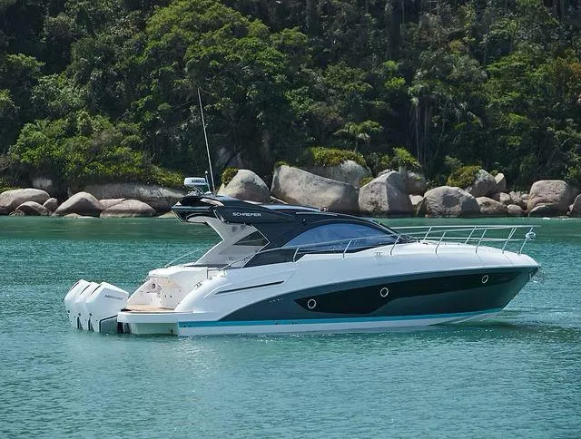  Yacht Photos Pics 2026 Schaefer 400 yacht on turquoise water near rocky shoreline.