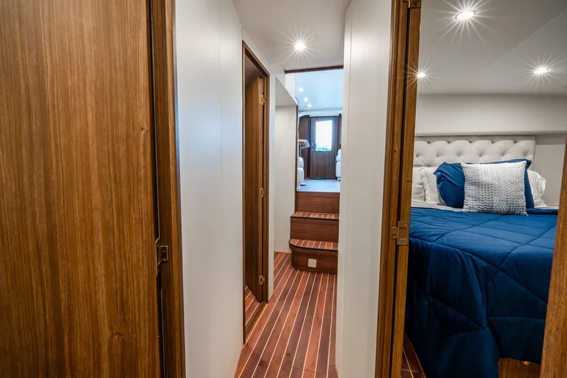 Knotty Girl Yacht Photos Pics Interior hallway of a 2005 Viking 52 Convertible yacht with wooden doors and a cozy bedroom.