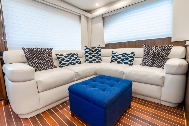 Knotty Girl Yacht Photos Pics Luxurious interior of a 2005 Viking 52 Convertible yacht with white leather seating and blue ottoman.